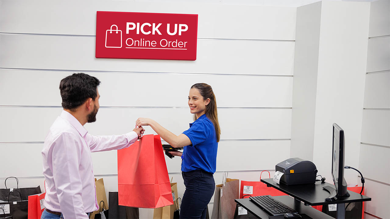 A retail associate hands a BOPIS order to a shopper in the pickup area