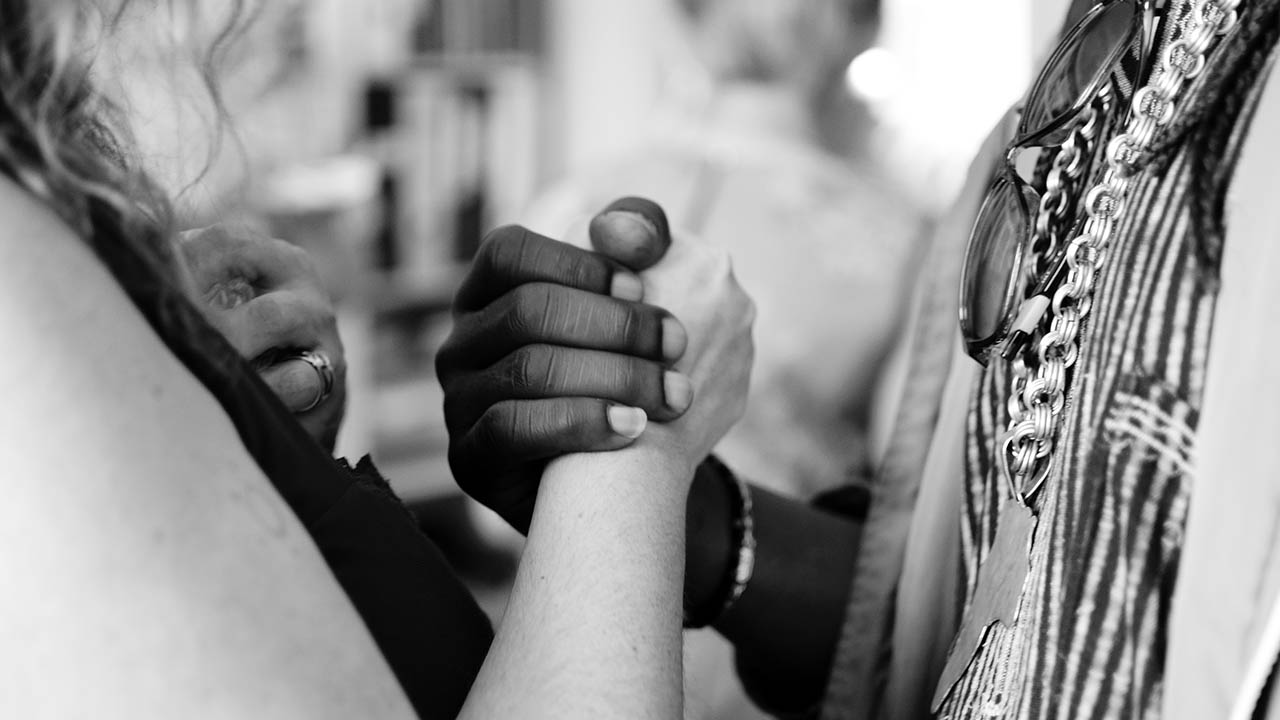 A black woman and white woman hold hands in a sign of unity