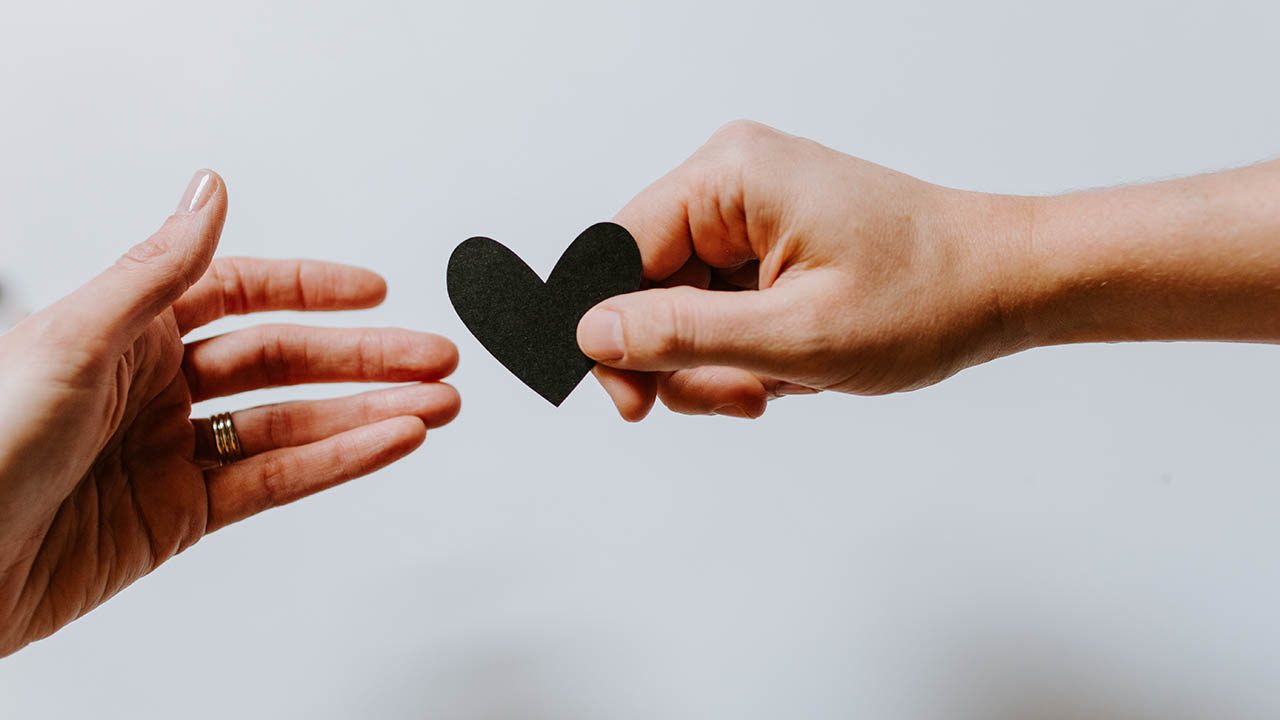 A person hands a paper heart to someone else
