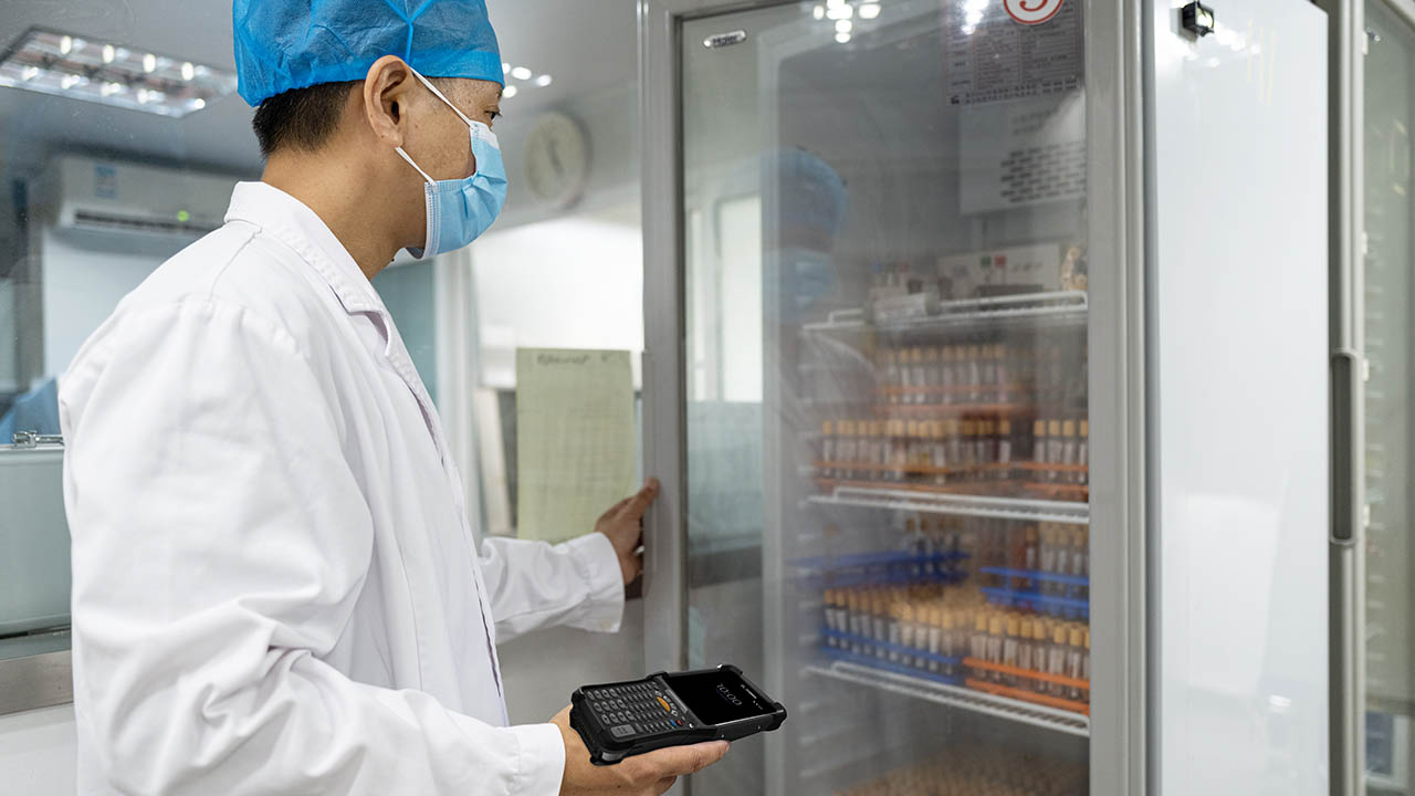 A cold chain worker looks in a pharmaceutical refrigerator