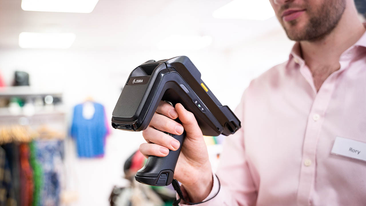 A retail associate holds a handheld Zebra RFID reader