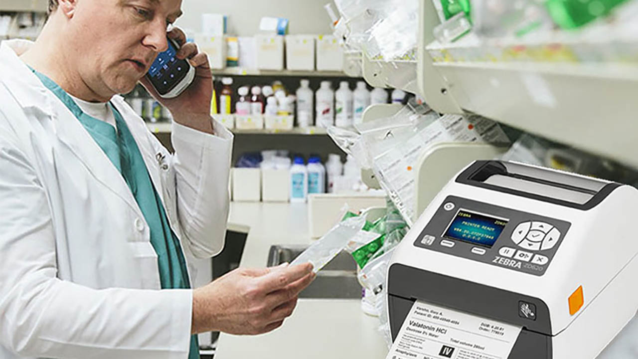 A pharmacist pulls a label off a Zebra thermal printer 