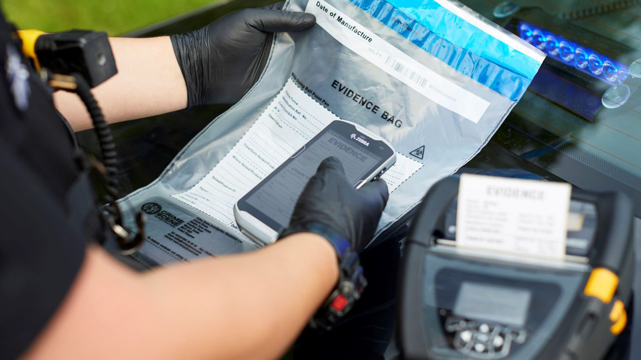 A police officer uses a zebra mobile computer and mobile printer to tag an evidence bag and enter it into the automated inventory management system