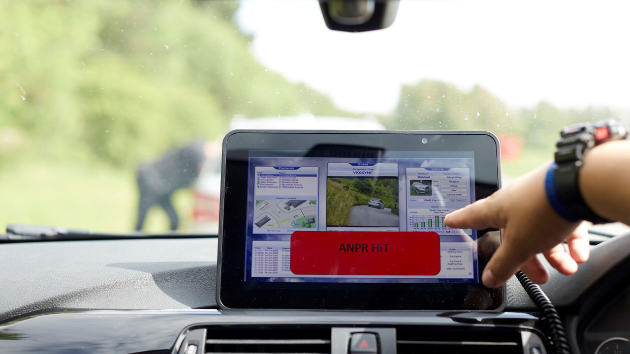 A police officer uses a rugged tablet mounted on the dashboard of the patrol car