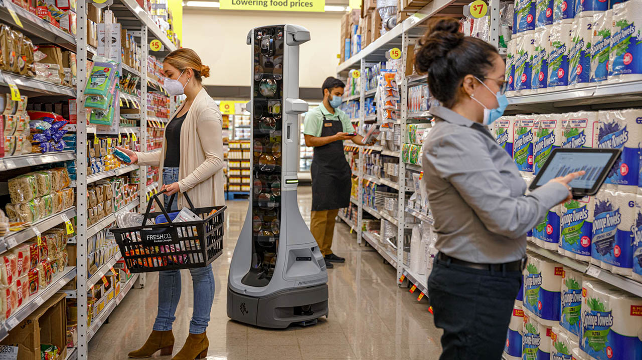The Zebra EMA 50 enterprise mobile automation system navigates around two grocery store associates and a shopper in an aisle