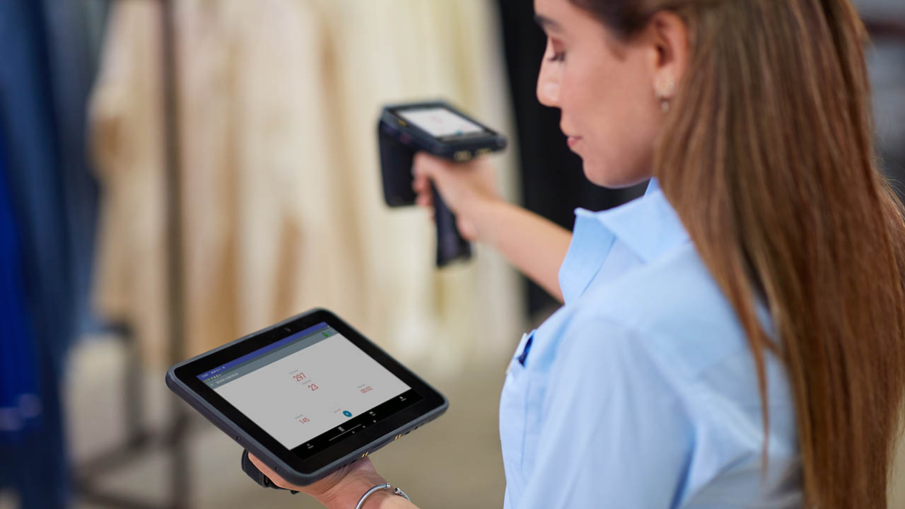 A retail store associate uses a mobile computer with an RFID sled and a tablet to conduct an inventory count