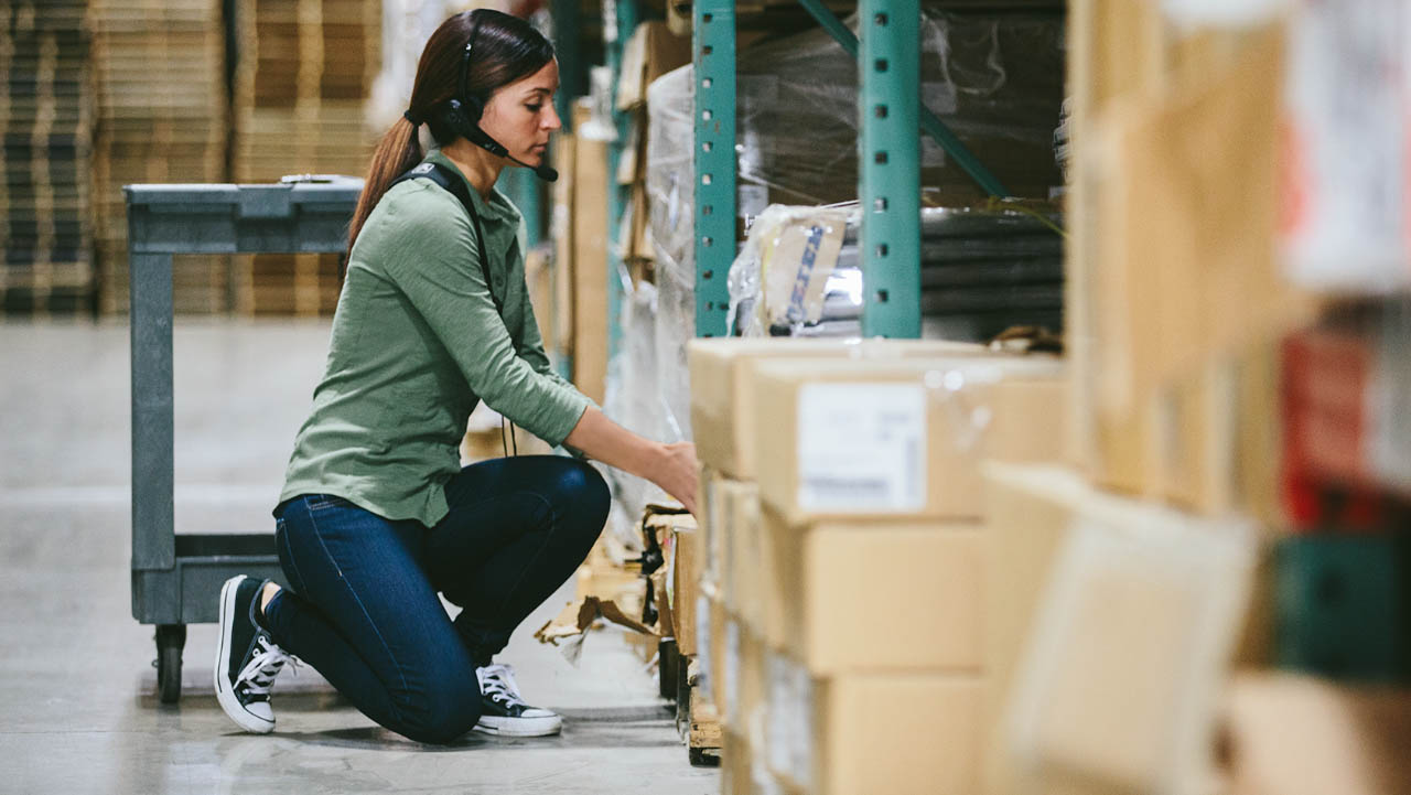 A warehouse worker uses voice technology to assist with picking tasks