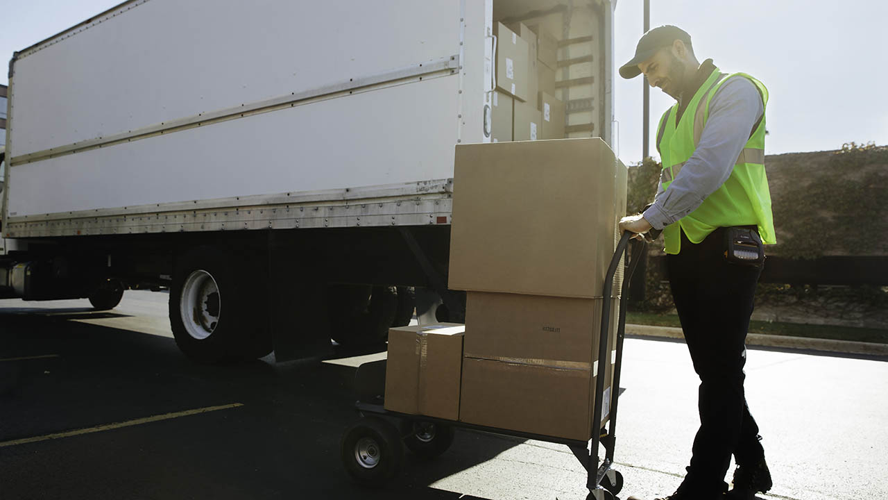 A deilvery driver unloads packages from a tractor trailer