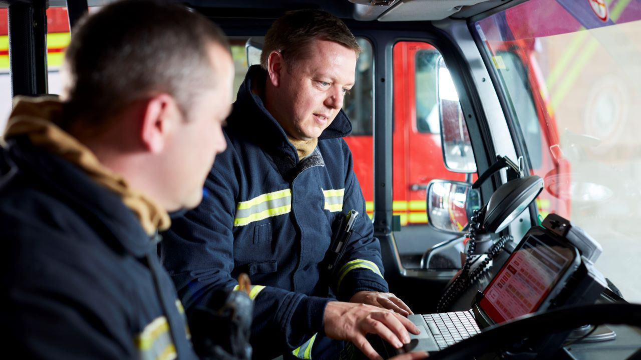 Firefighters look at a rugged tablet mounted in their fire truck