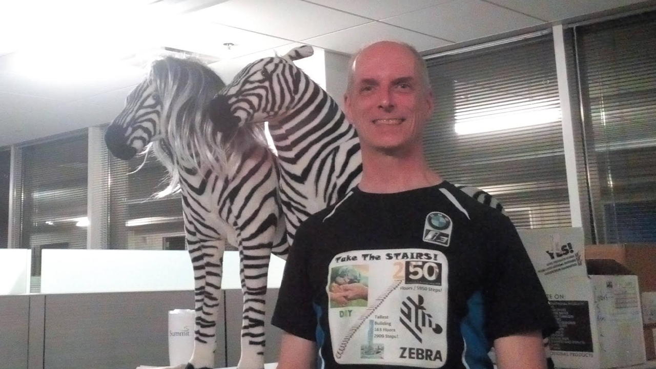 Dave Dipert, Senior Electronics Engineer at Zebra, standing in front of two toy zebras