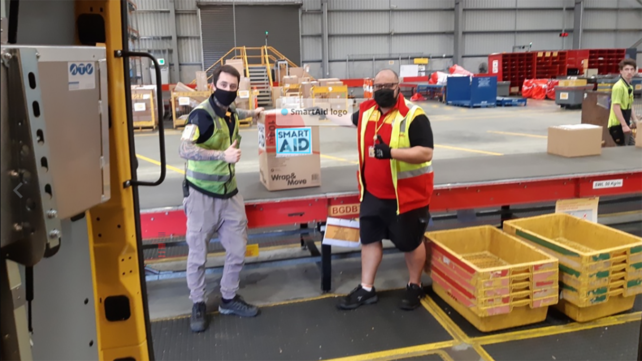 Wizy Gives Back to Smartaid Warehouse Workers Blog Photo SmartAid warehouse workers give a thumbs up