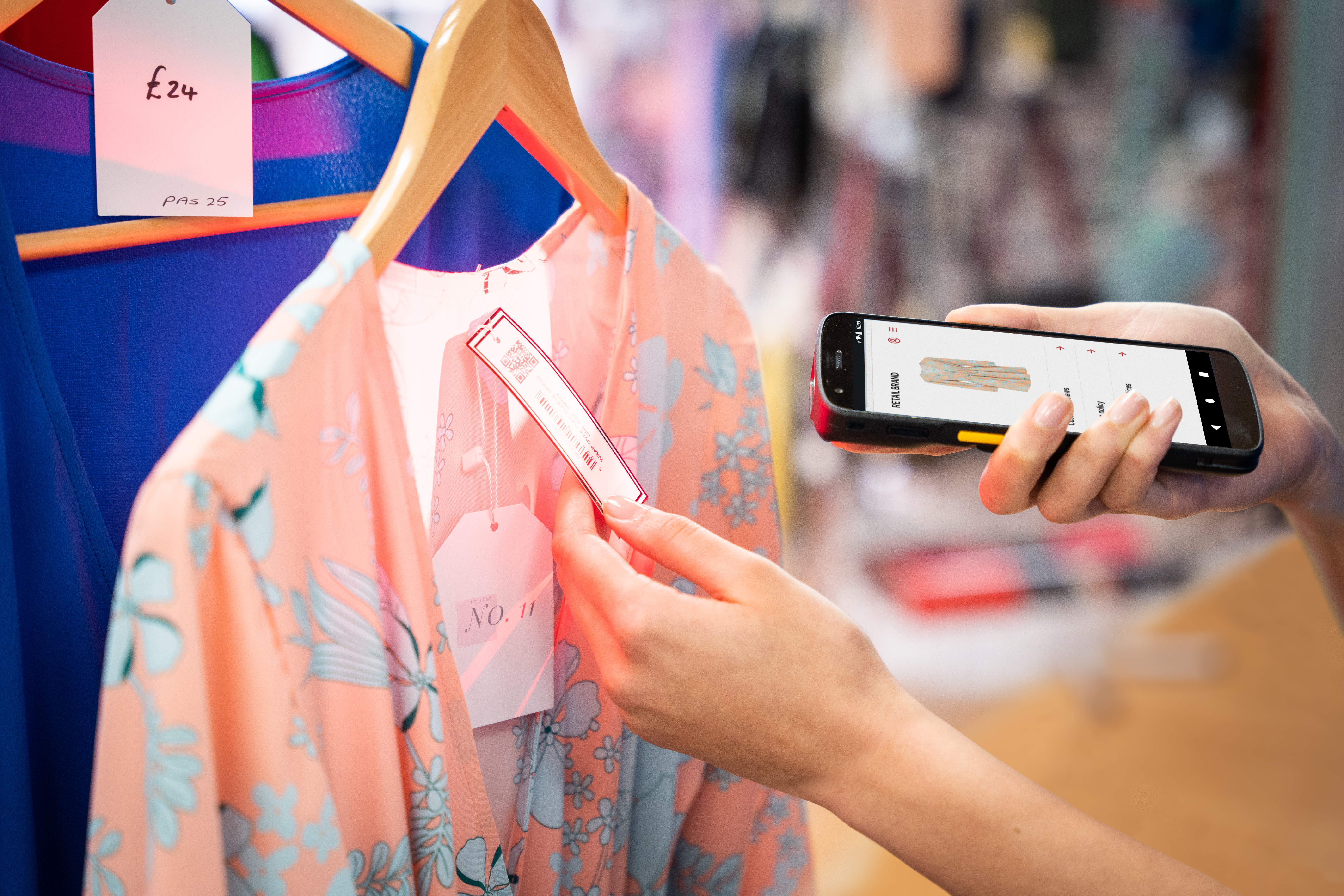 Close up of a retail worker at an apparel store, using a TC22 to scan 2D GS1 Digital Link labels and 1D barcode labels.