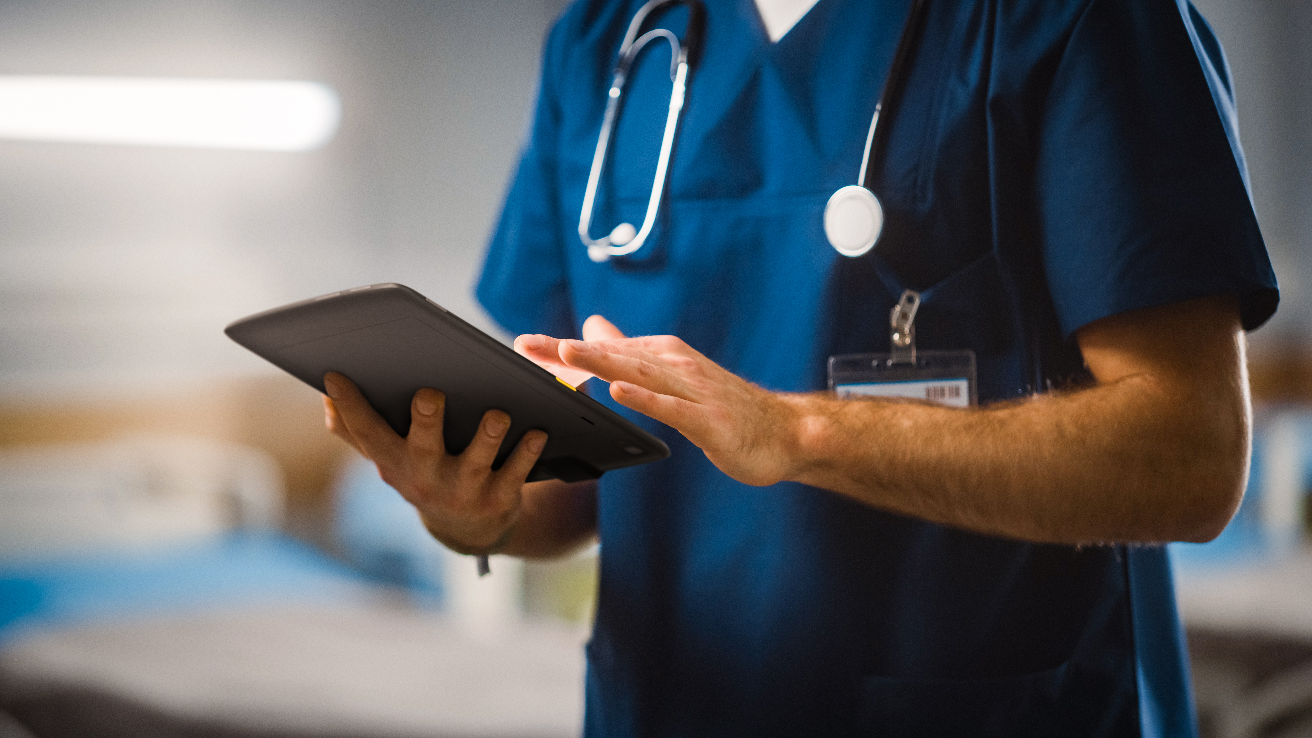 A medical professional using a Zebra tablet inside of a hospital.