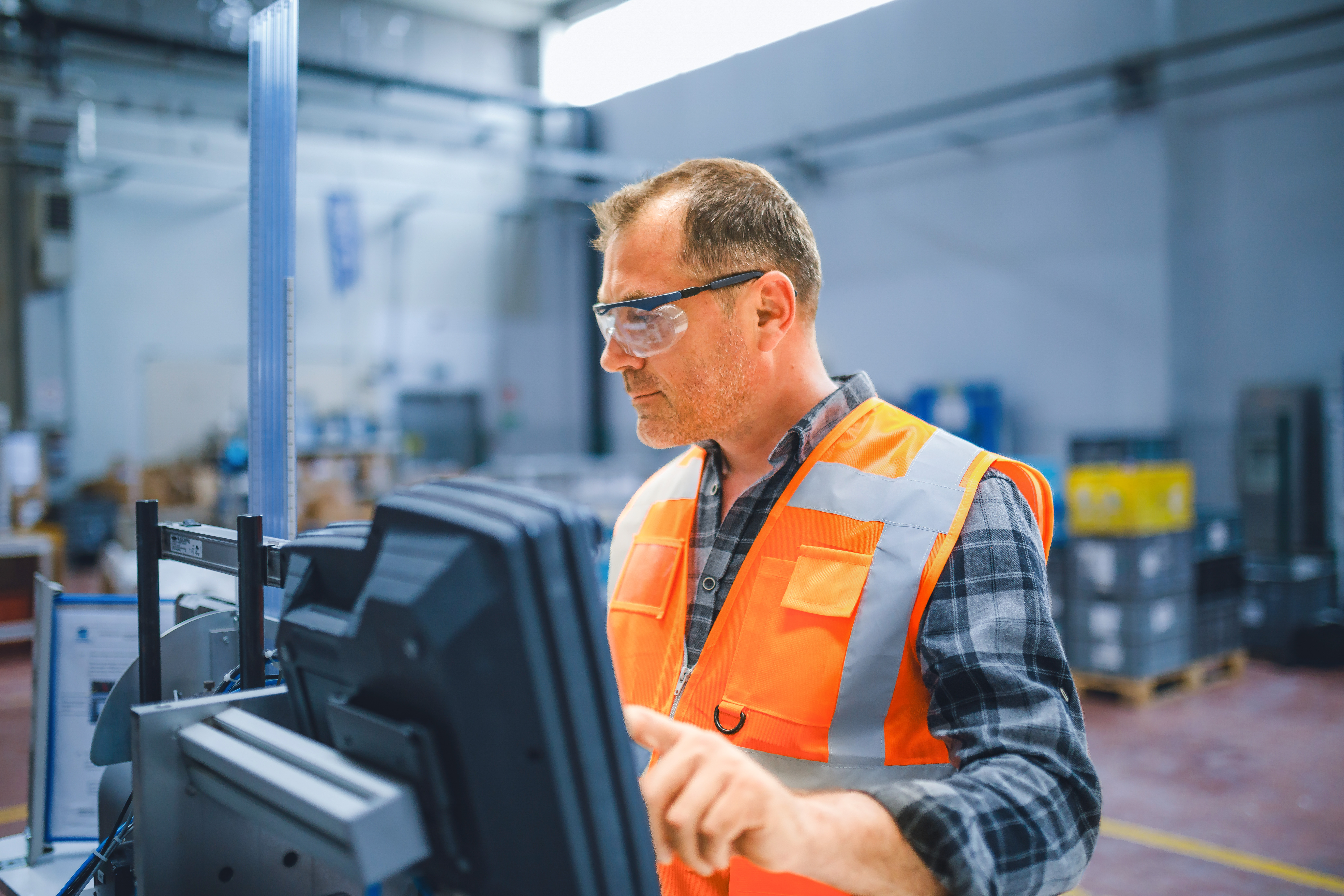 An industrial worker is using equipment in a factory.