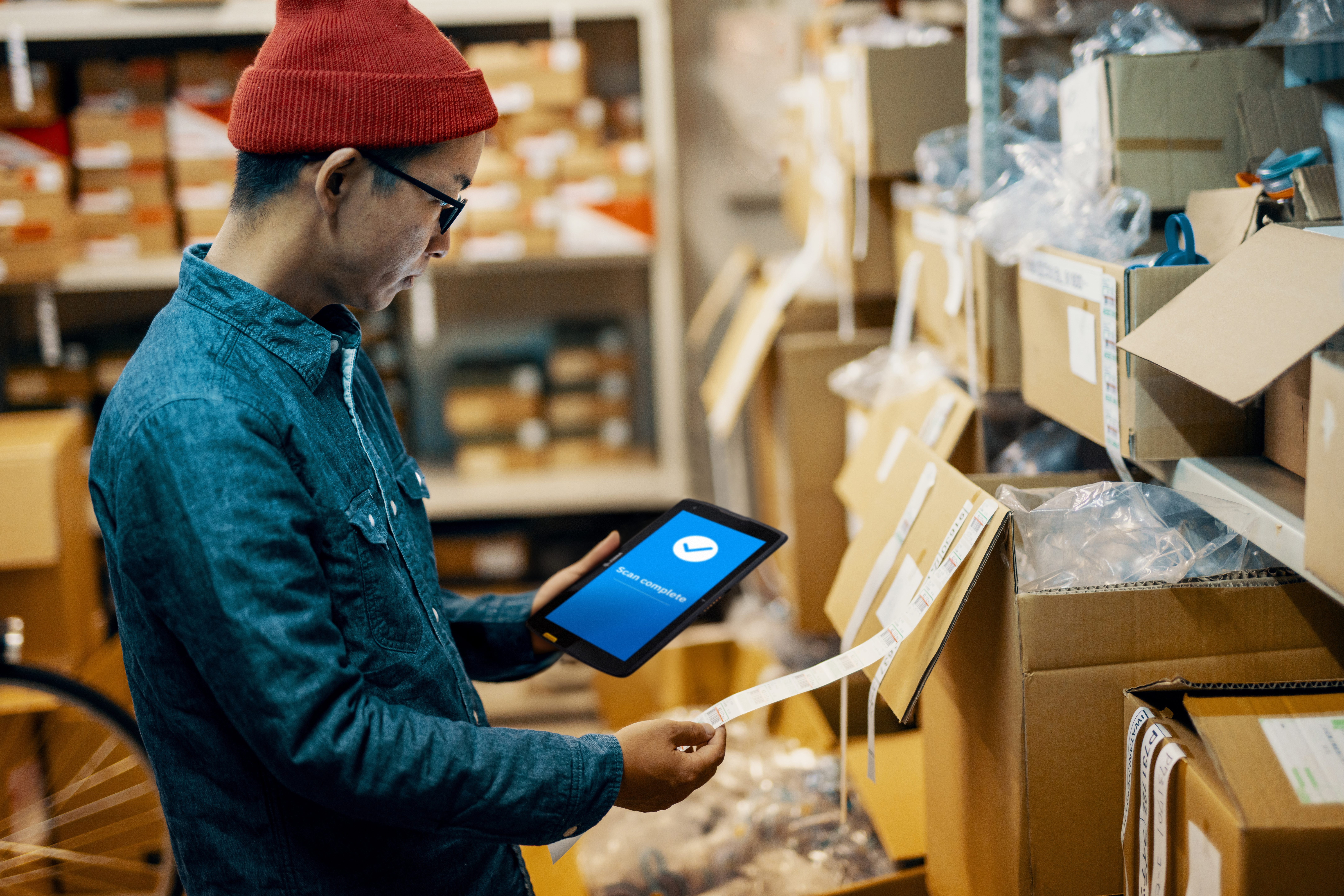 A retail employee using a  tablet to check inventory inside of a back-of-house store room.