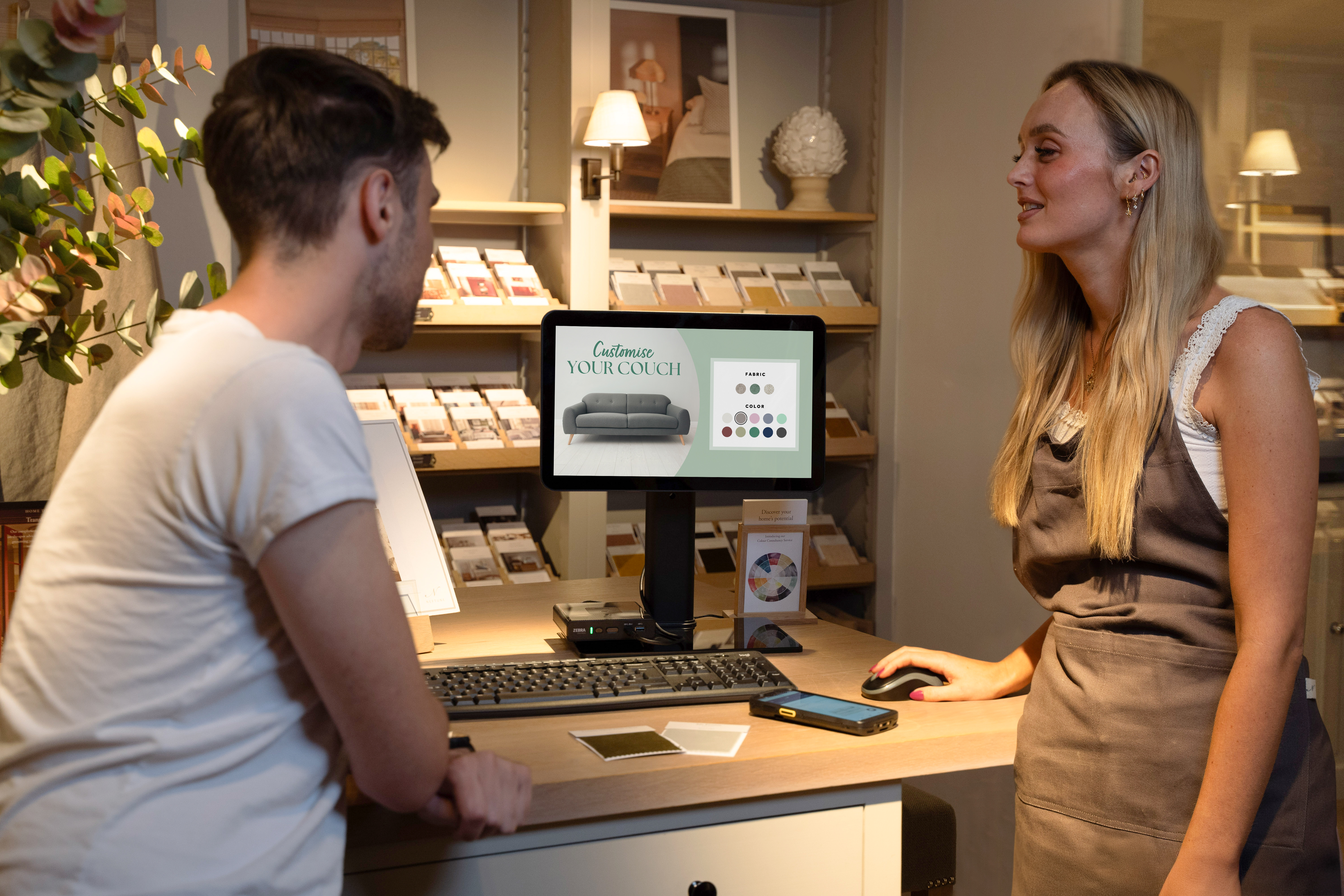 A retail associate using ZEC500 as a workstation with TD50 to assist a customer, TC53 is in the background