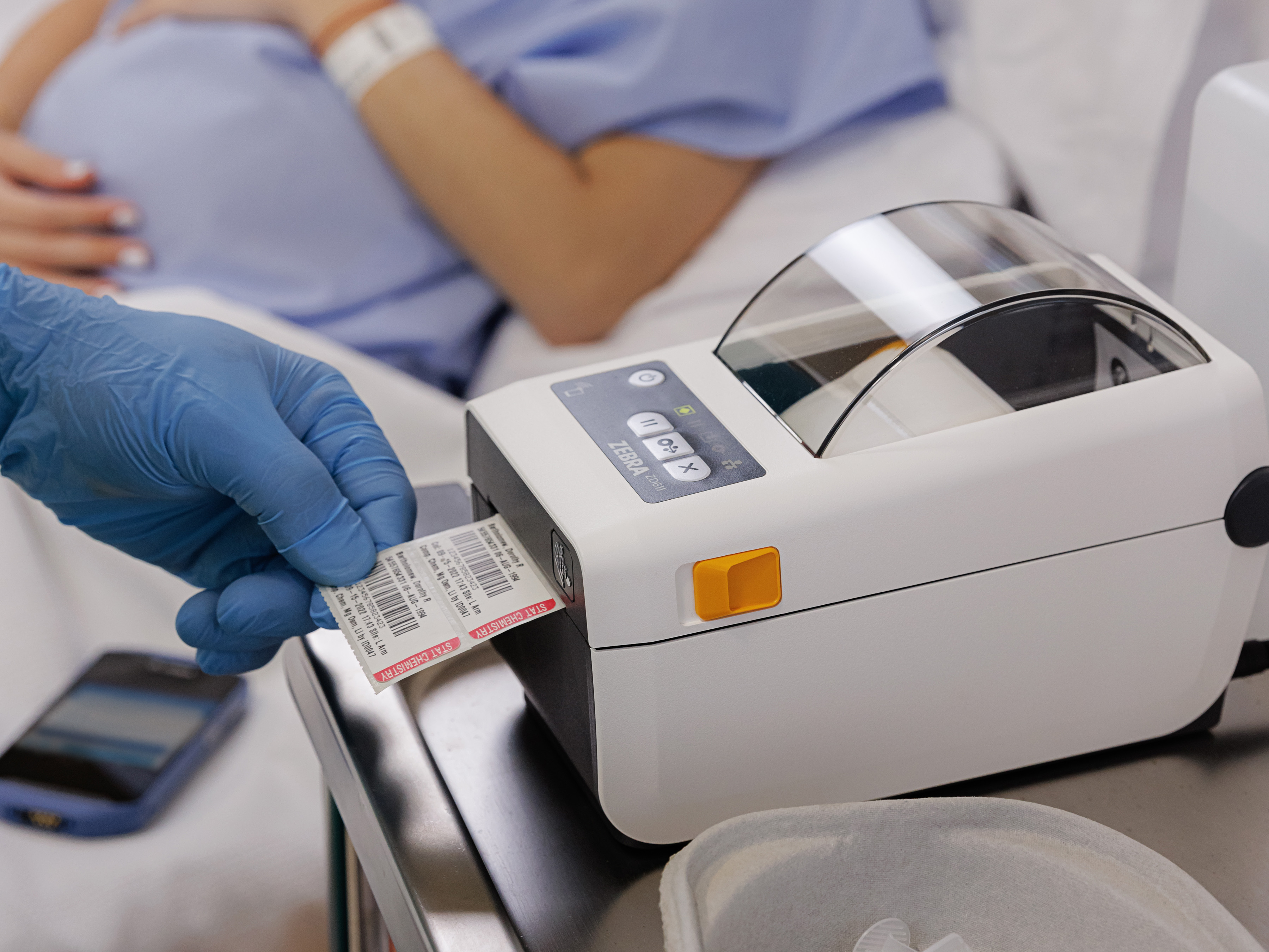 Top right view of a Zebra ZD611d-HC healthcare printer near patient on bedside table