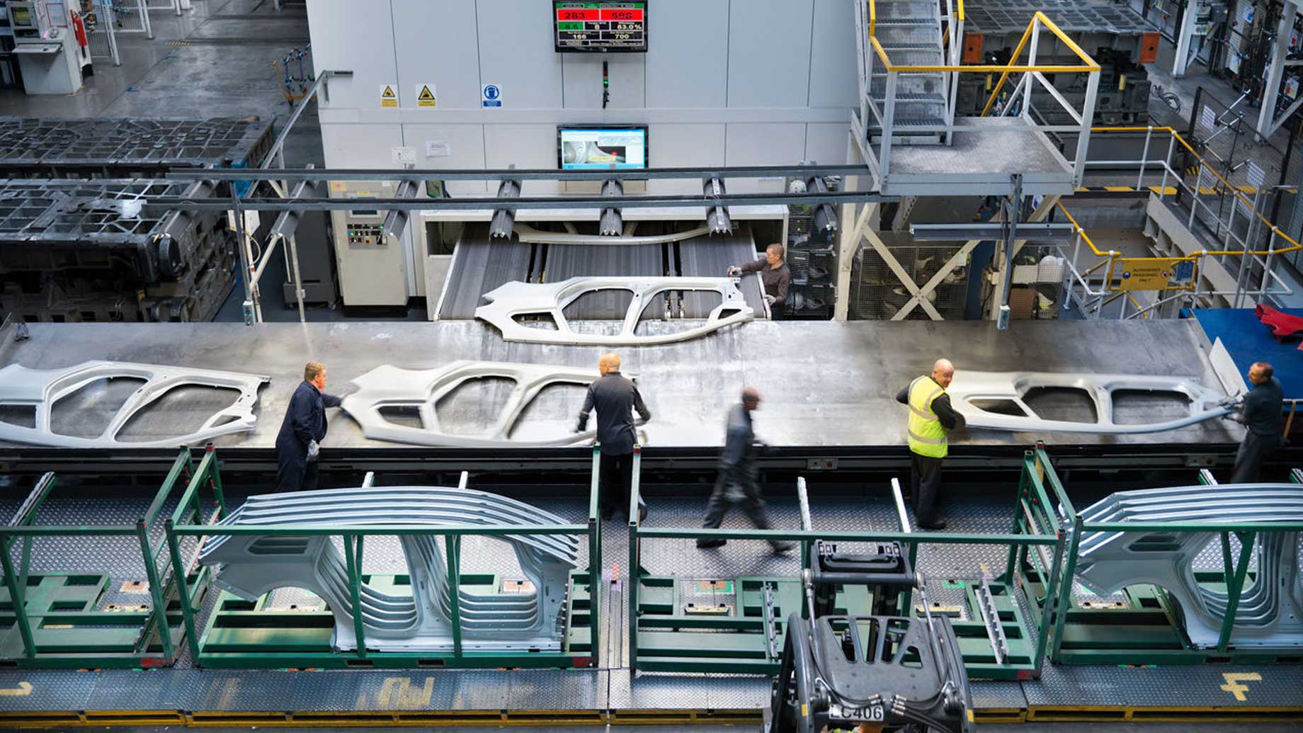Workers inspect automotive body panels in factory setting