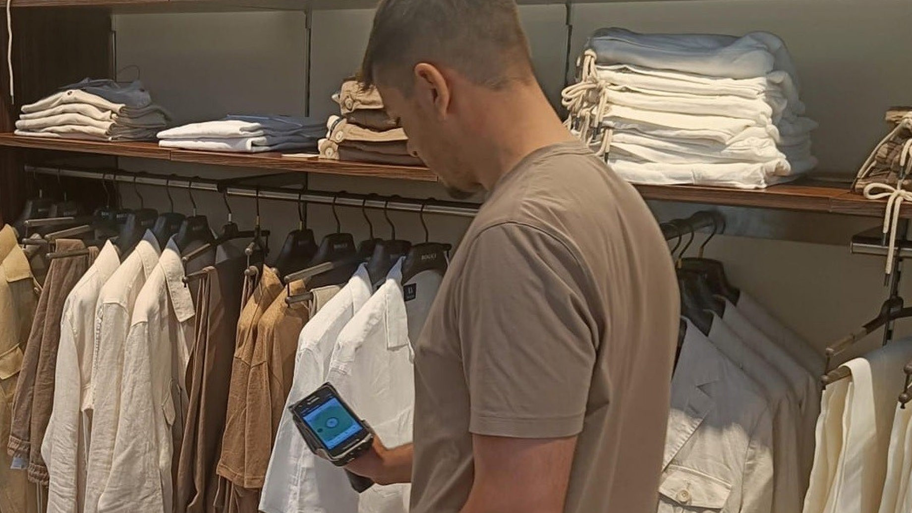 Man shopping for clothes while using smartphone at Boggi Milano