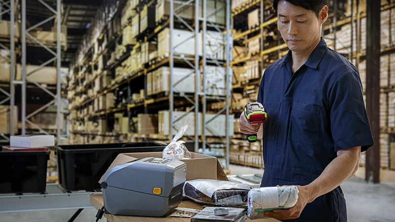Three Trends Shaping Retail Fulfillment Man Using Zebra Scanner and Zebra Printer on the Desk