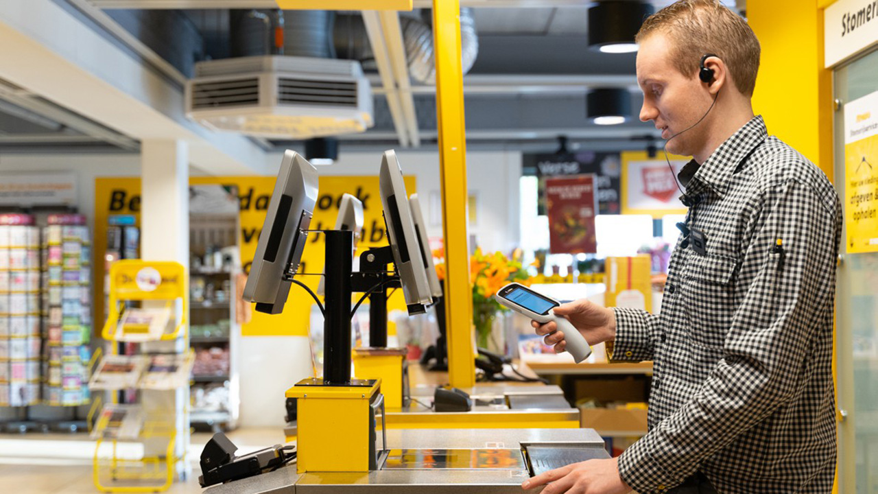 Retail worker scans item with Zebra scanner at modern checkout counter