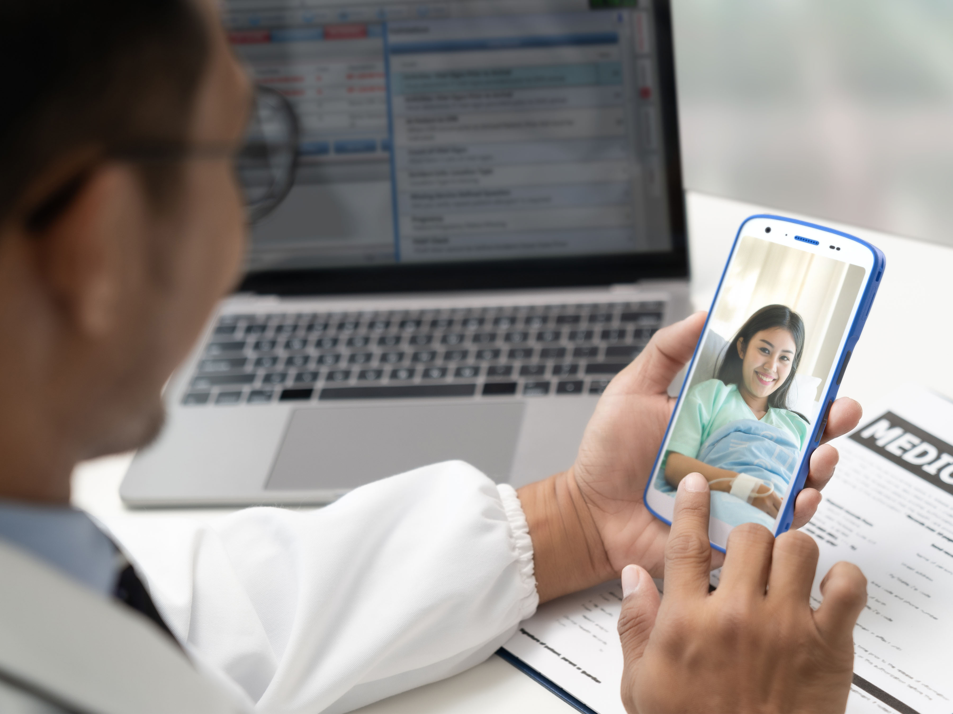Application photography illustrating a compassionate and modern clinical interaction between a doctor/healthcare worker and a patient in a hospital room, utilizing the Zebra HC55 rugged healthcare mobile computer.