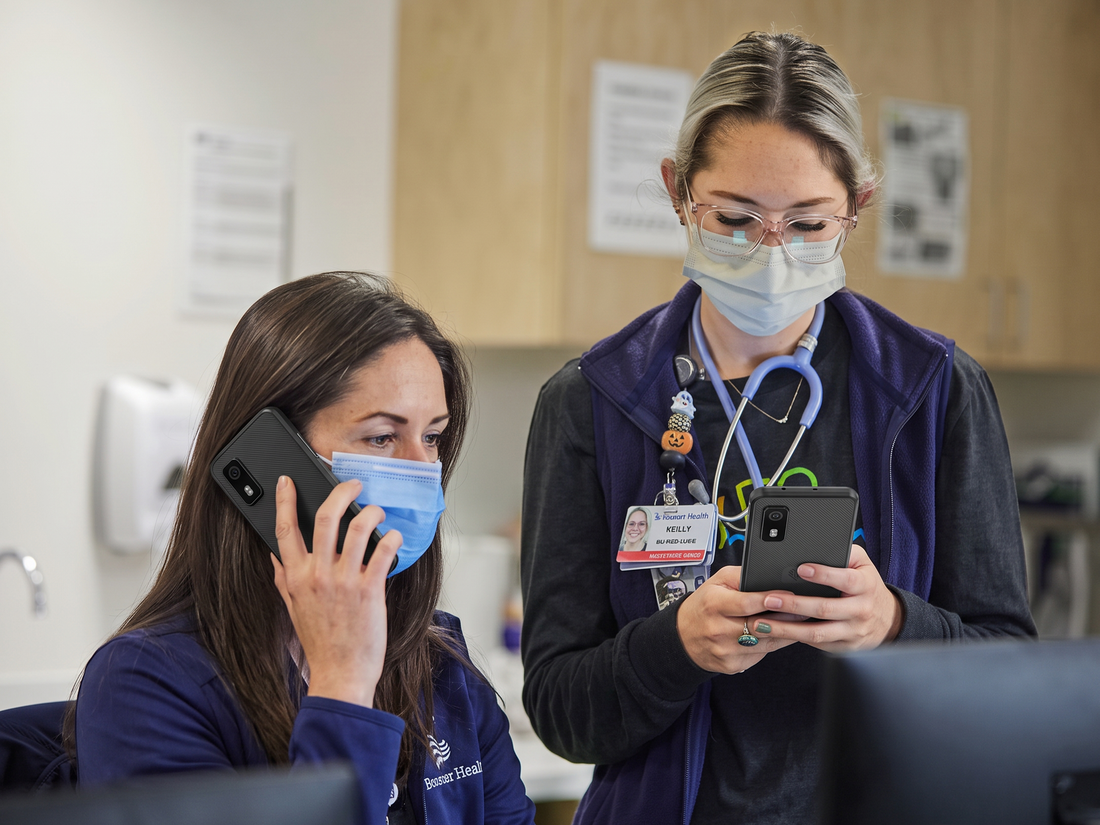 Healthcare workers use black Zebra EM45 Enterprise Mobiles to securely log in and coordinate patient care at a clinical workstation.