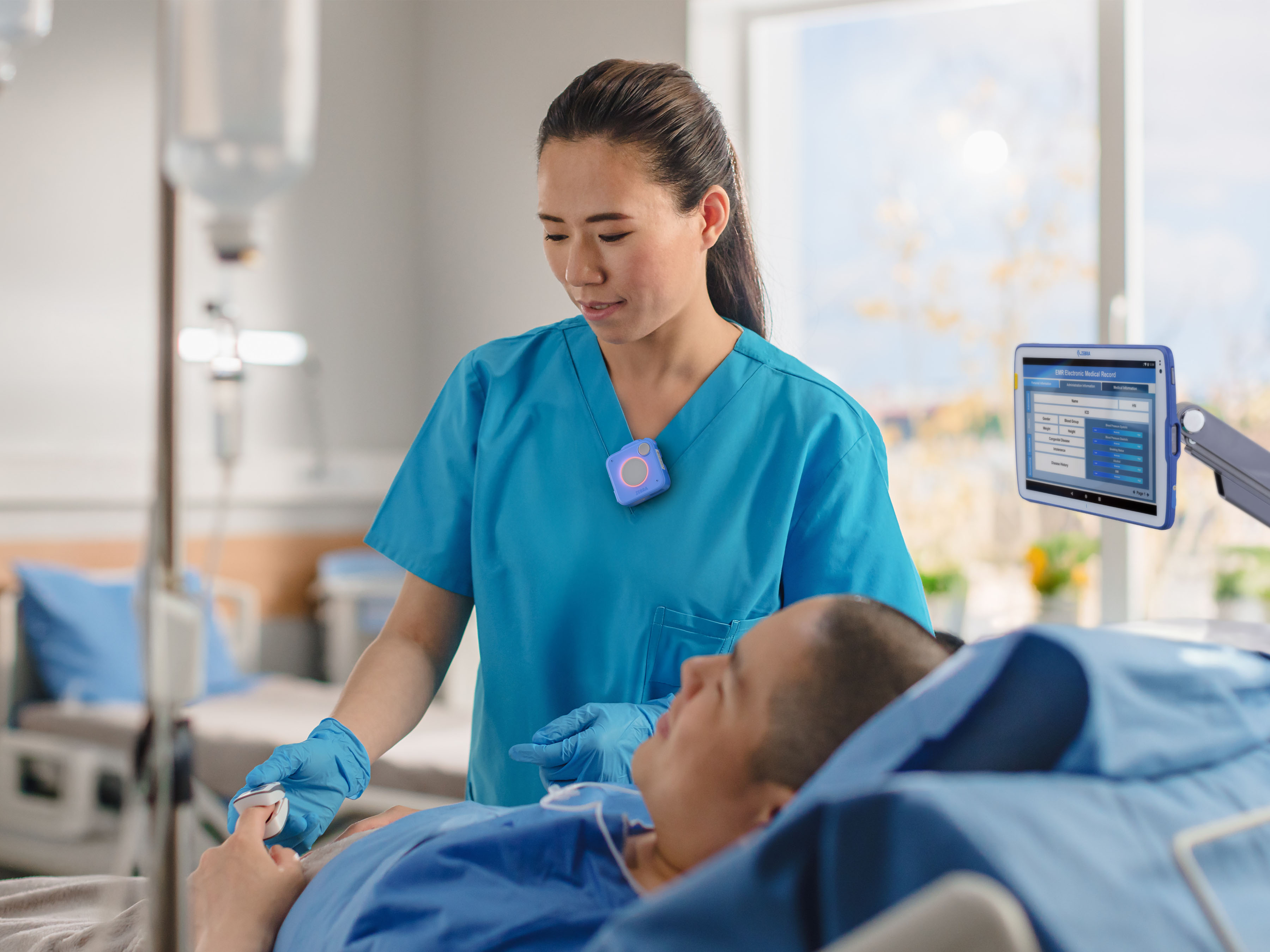 Healthcare nurse using Zebra WS101-H to communicate at patient bedside.