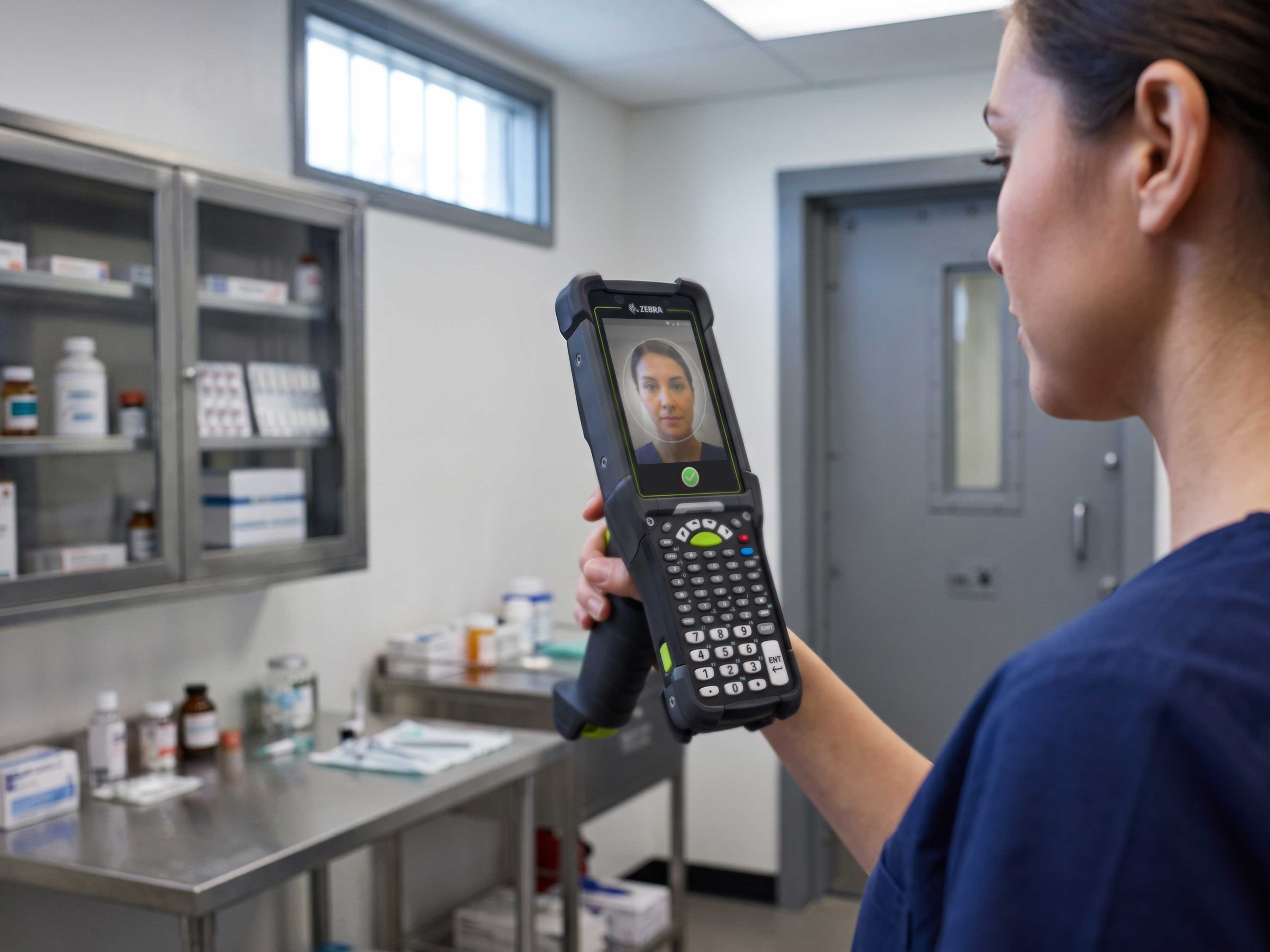 A healthcare professional uses a Zebra MC9400 mobile computer with Identity Guardian for facial recognition to ensure secure mobile point-of-care prescription dispensing to an inmate.