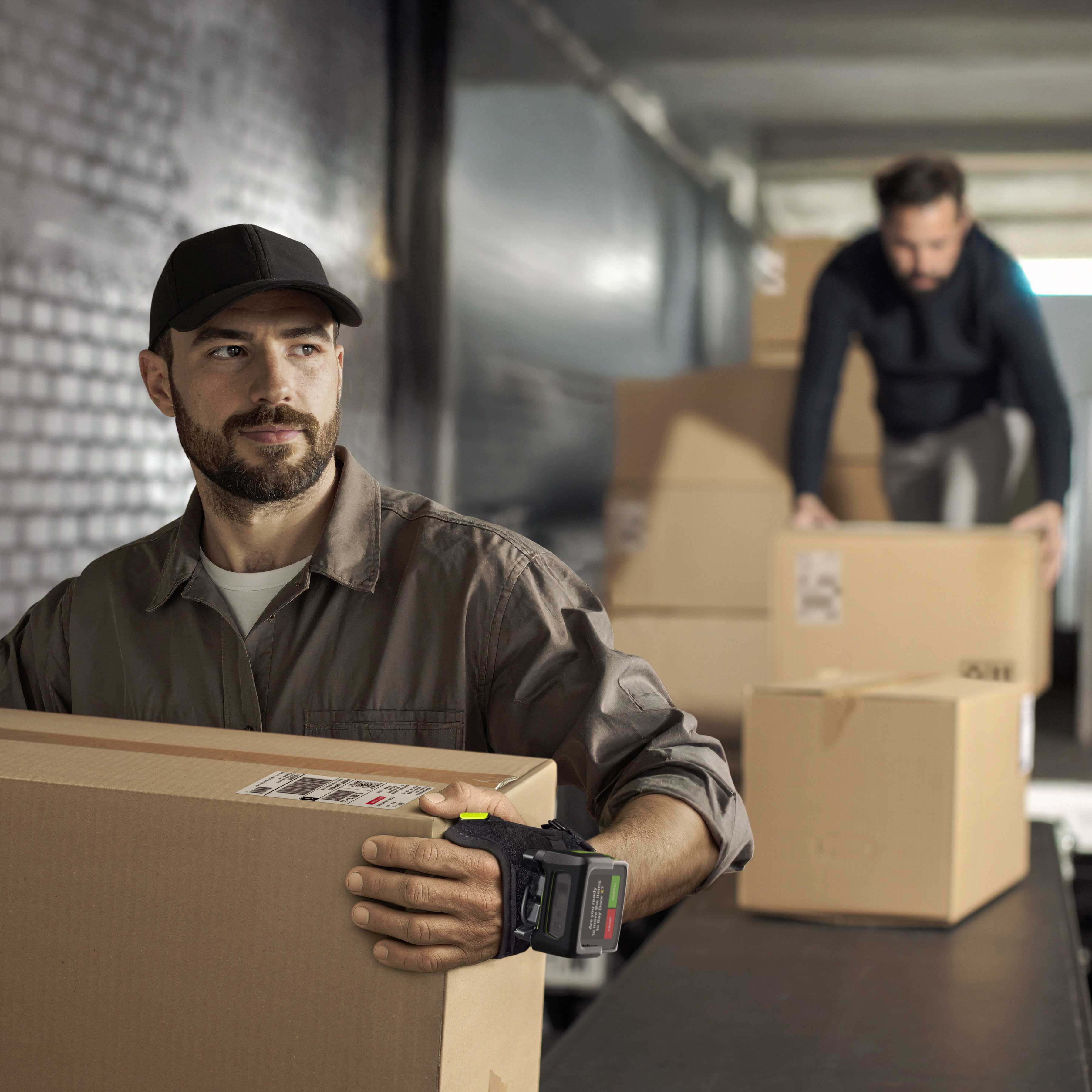 A logistics worker uses a Zebra WS501 back-of-hand mount computer to receive packages as they are being unloaded from a truck.