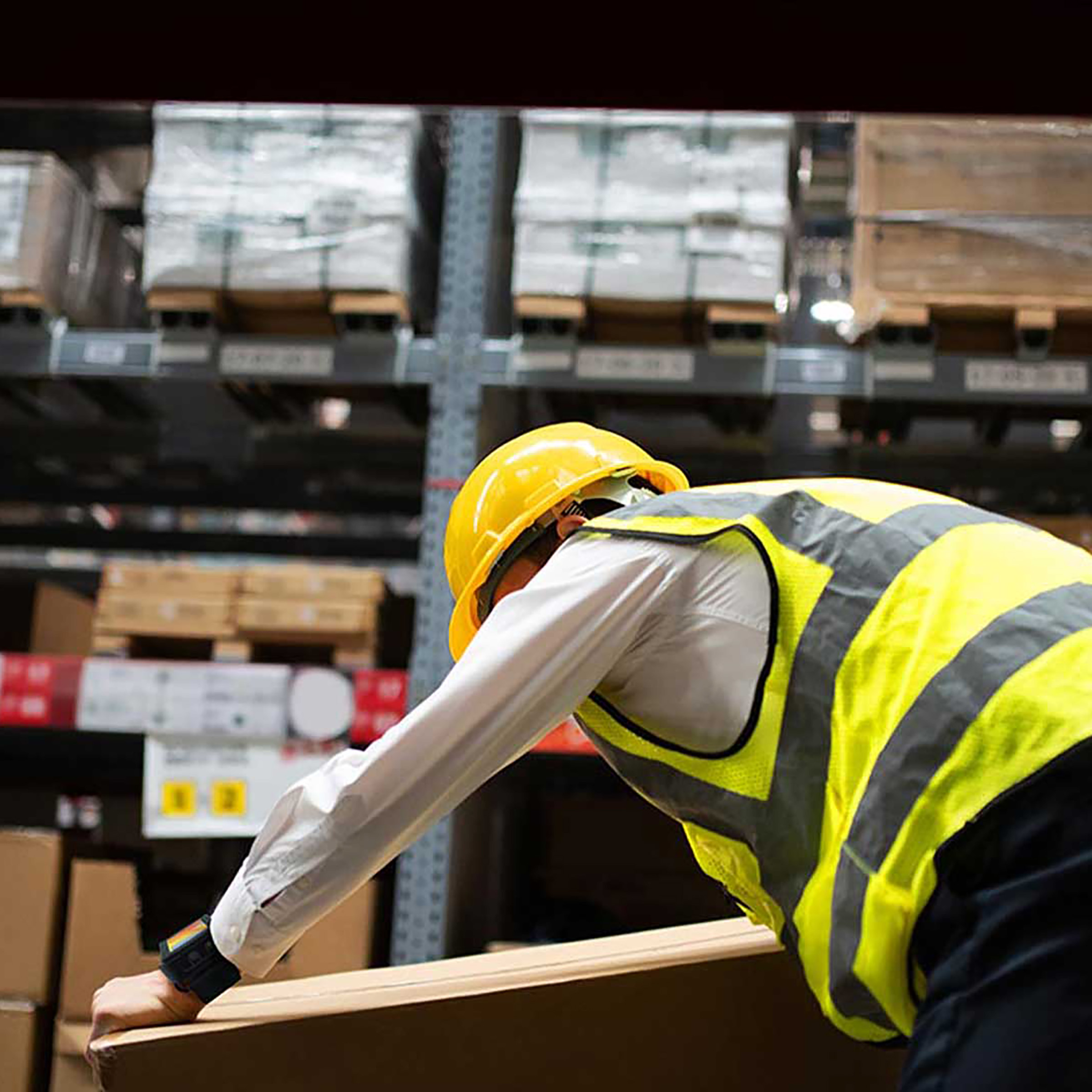 Warehouse employee with WS301 on his wrist picking up a box.