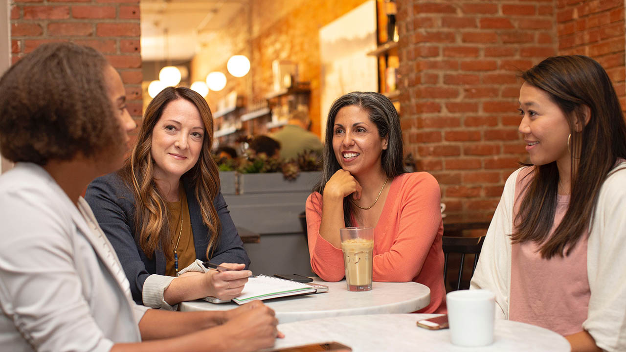 Women sit around a table talking