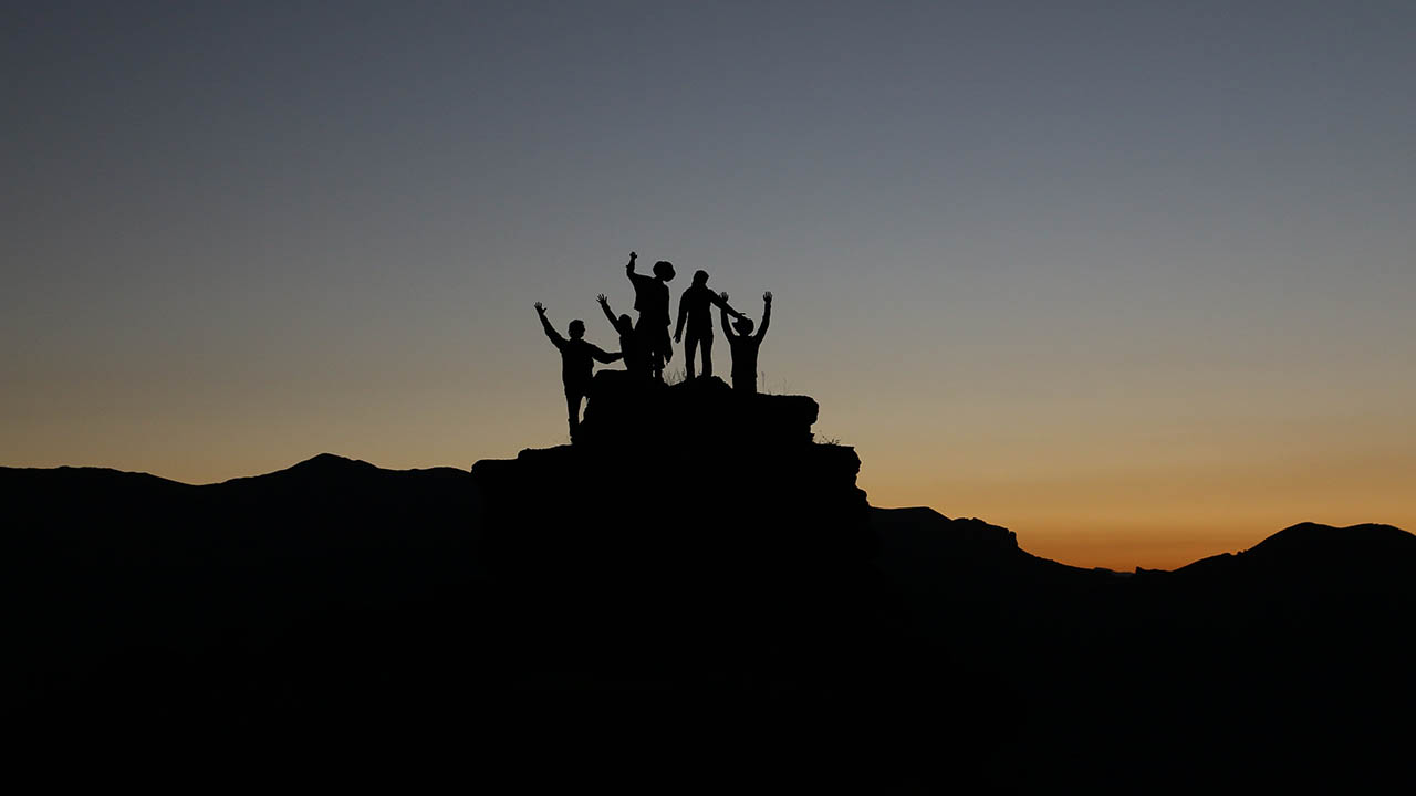 A team celebrates after reaching the top of a mountain 