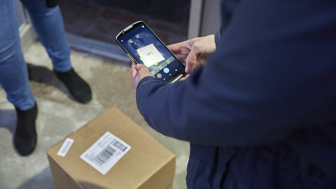 A courier uses the Zebra Mobile Dimensioning software on a Zebra TC53 mobile computer to get the measurements for a package being picked up at a residence