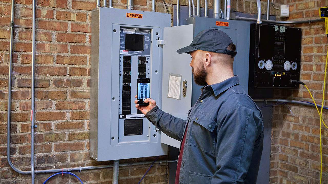 An utiltiy field technician uses a Zebra TC58 5G mobile computer to diagnose an electrical panel