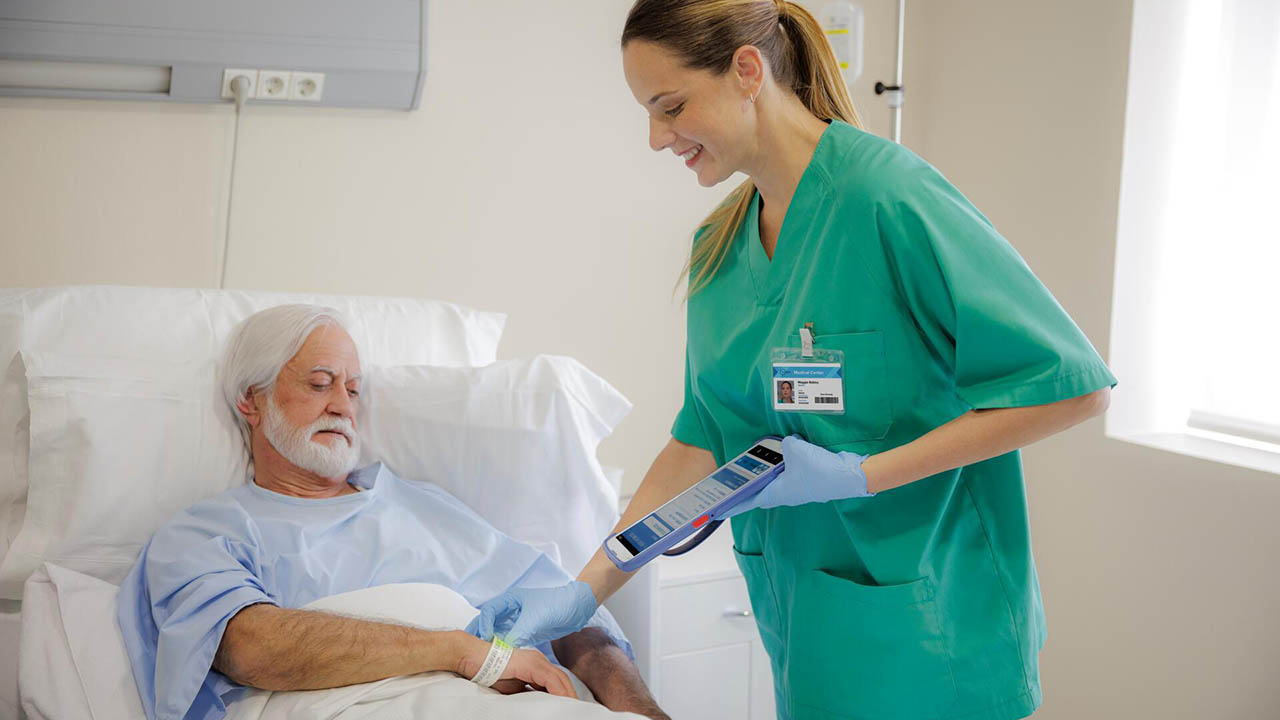 A nurse uses a Zebra ET4x-HC healthcare rugged tablet to scan a patient's wristband and confirm identify