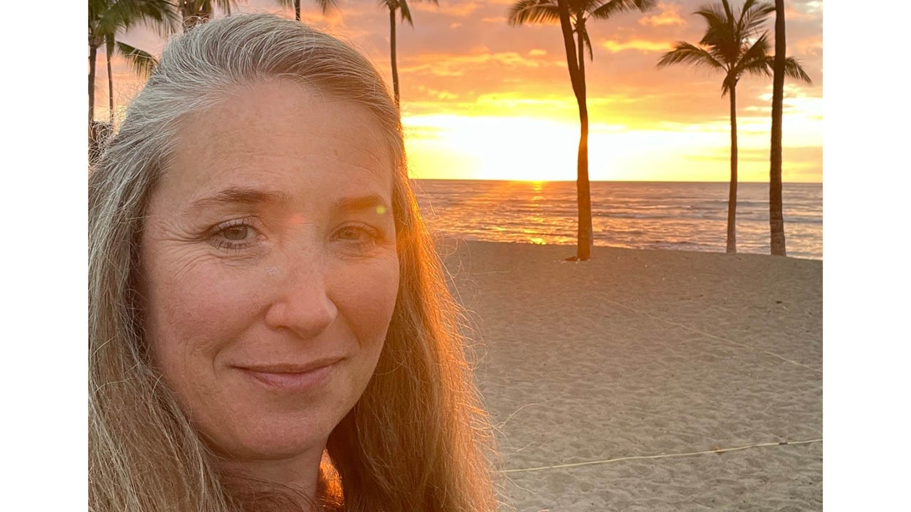 Jenna Stanley at the beach with a sunset in the background