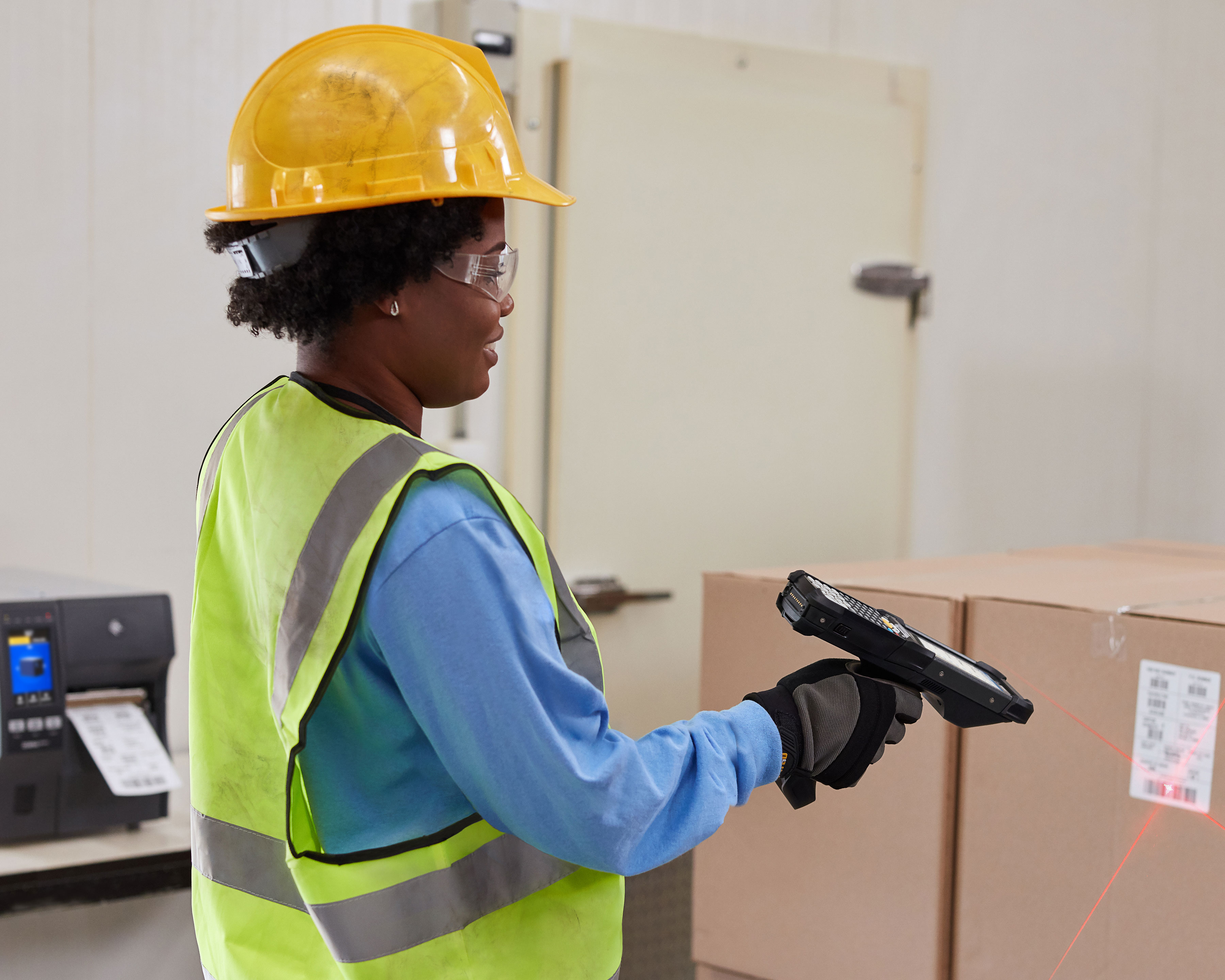 Warehouse worker holds Zebra MC9300 mobile computer to scan the barcode of a box 