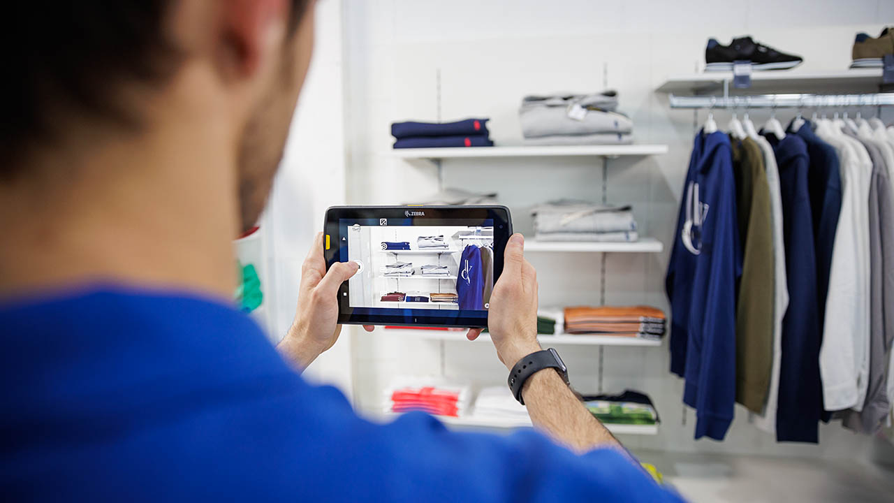 A retail associate takes a picture of shelf inventory using a Zebra tablet