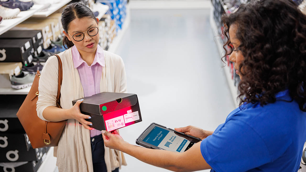 A retail associate uses a Zebra ET4x enterprise rugged tablet to price check a pair of shoes for a customer