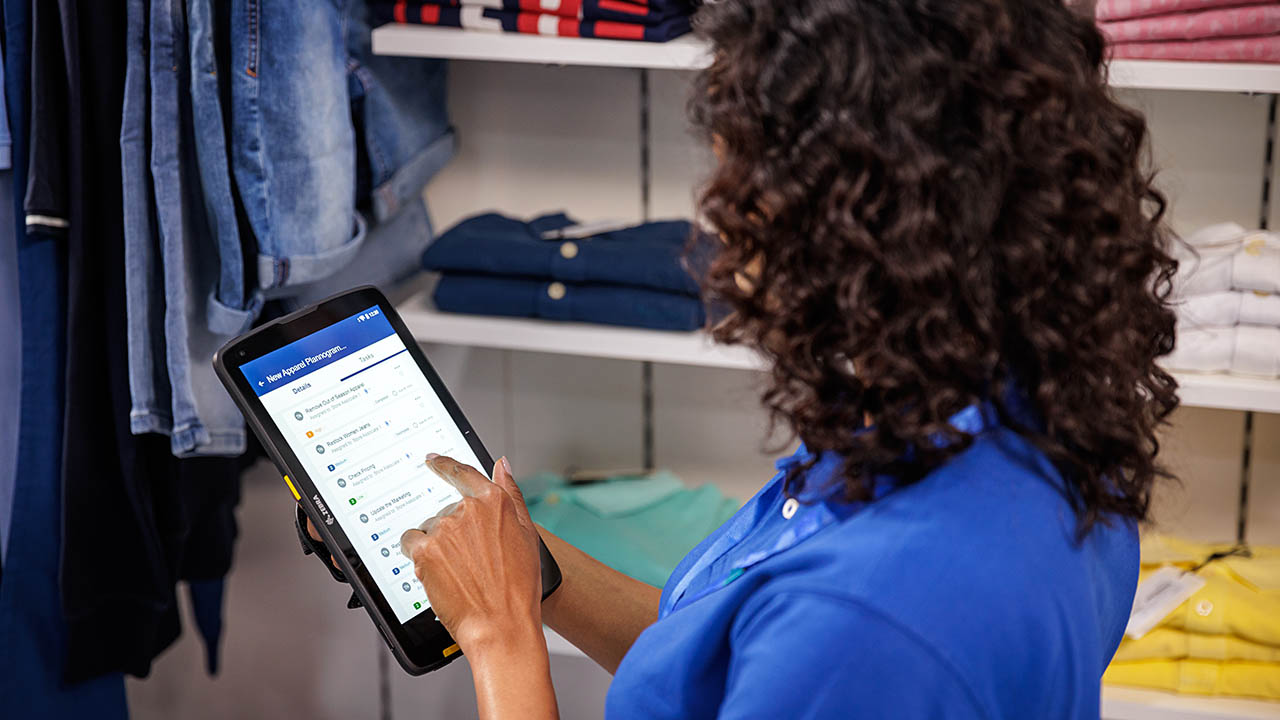 A retail store associate reviews a to-do list in the Reflexis Task Manager software app on a Zebra enterprise tablet