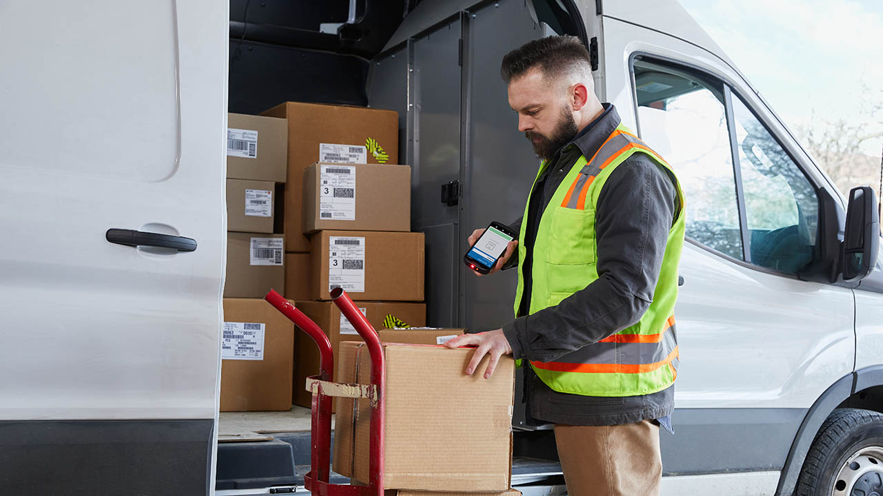 A delivery driver uses a Zebra TC58 mobile computer to scan the label on a box before leaving it with a customer