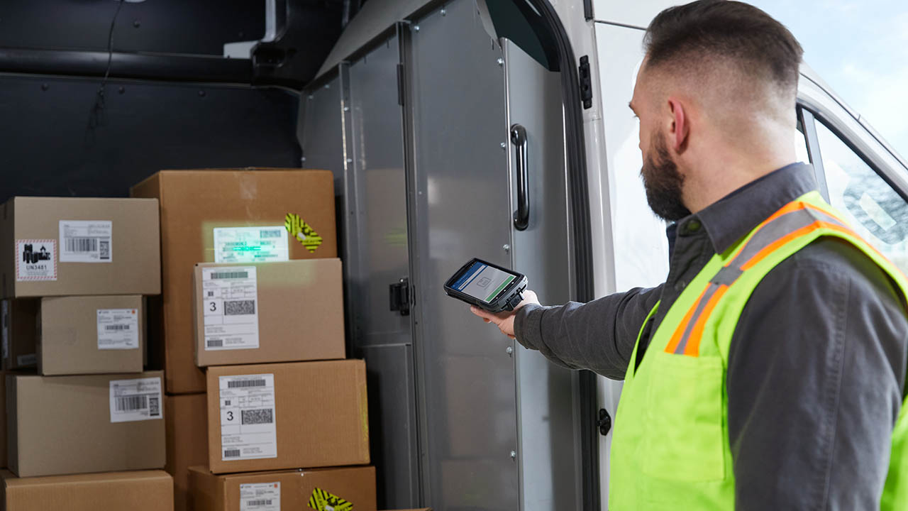 A retail associate uses a Zebra TC58 to scan the label of a package