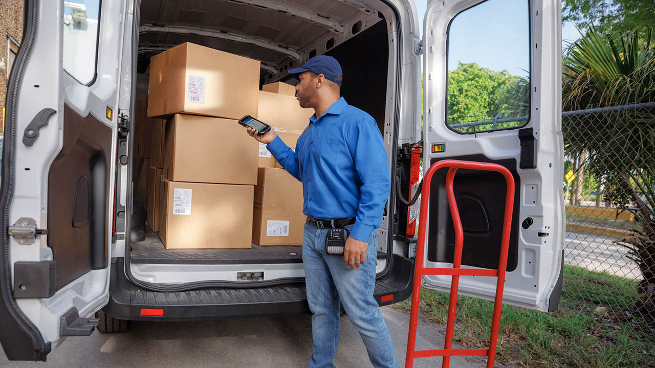 A delivery driver scans boxes in the back of his truck using a Zebra TC78 ultra-rugged mobile computer