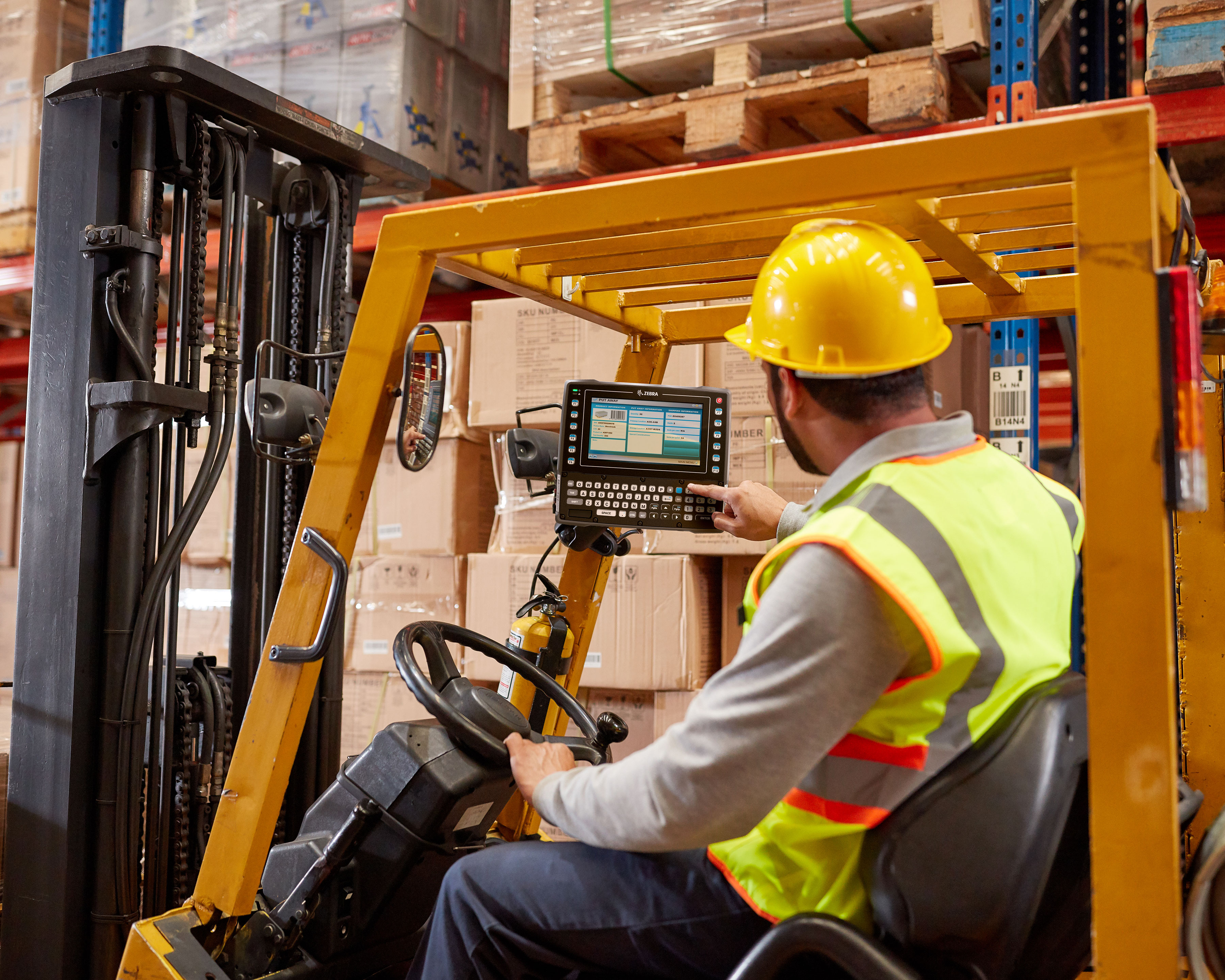 Worker looks at put away information uses a Zebra VC83x mobile computer that is mounted to a warehouse forklift
