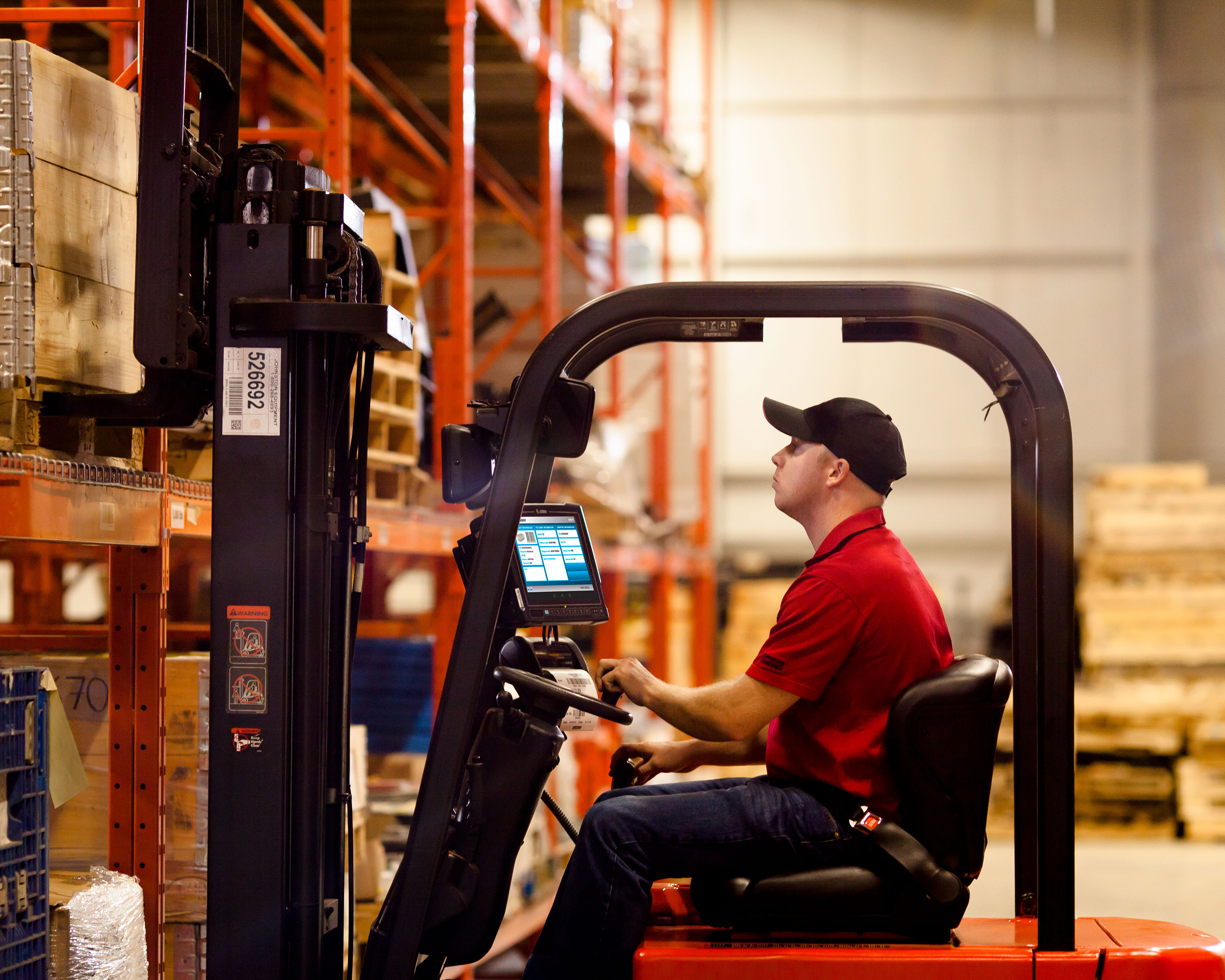 Worker uses Zebra VC83x mobile computer that is mounted to a warehouse forklift to accurately put away inventory on pallet racks