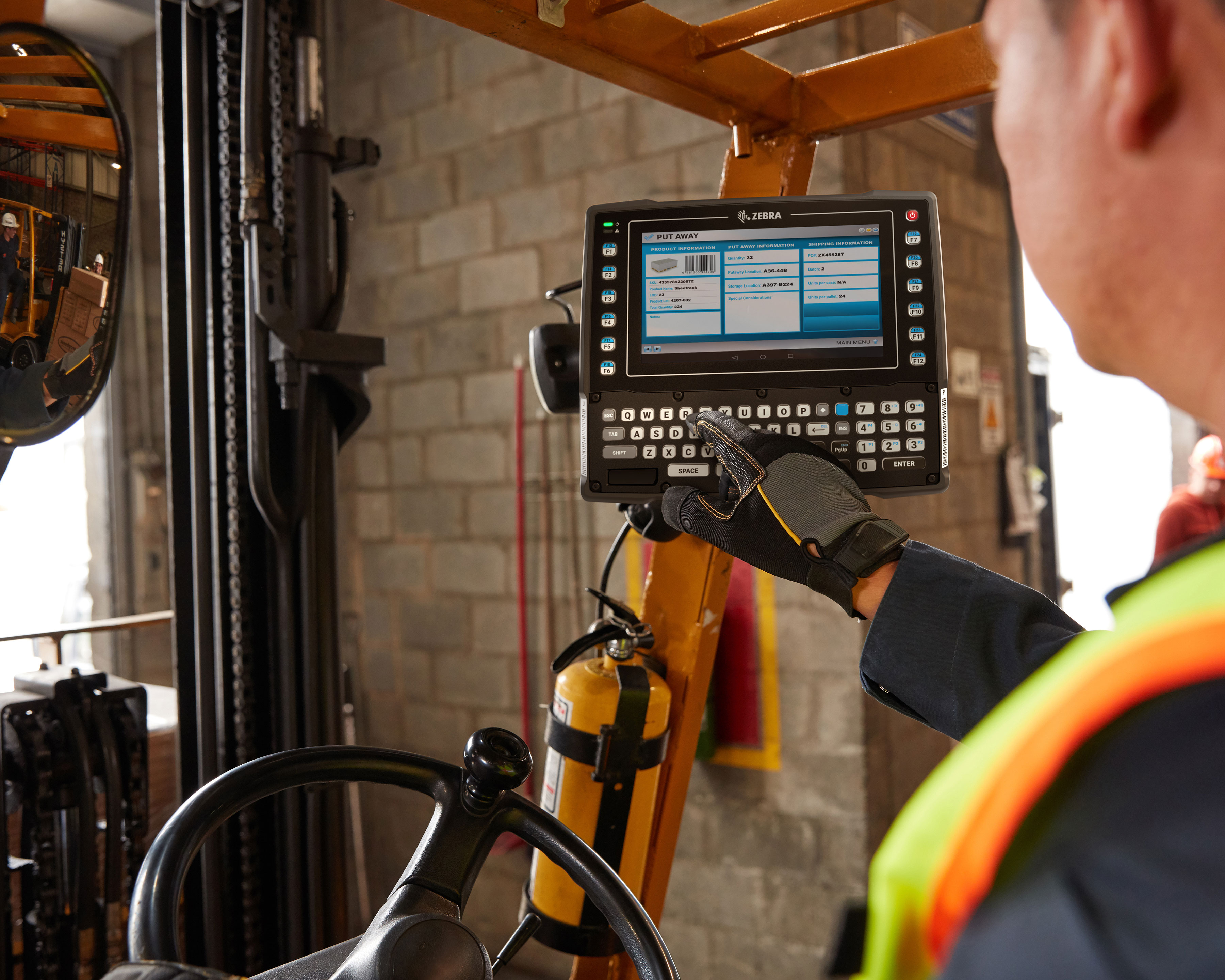 Worker checks information on a Zebra VC83x mobile computer mounted to a forklift prior to loading pallet boxes into a truck