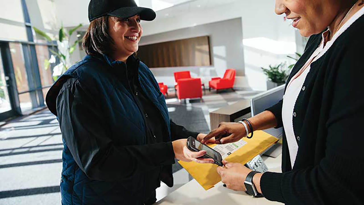 A courier asks a package recipient to sign for the package on her Zebra TC26 rugged enterprise handheld mobile computer