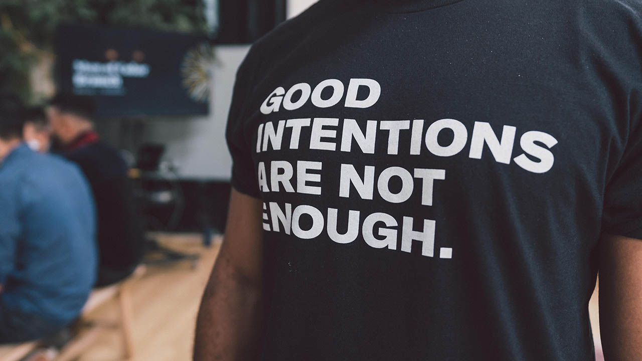 A man wearing a shirt that says, "Good intentions are not enough."