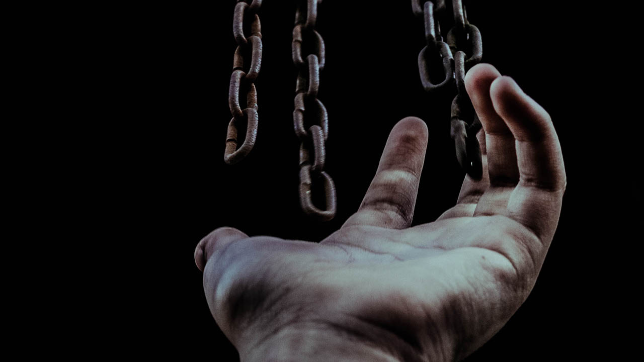 A black person holding up their fist with a rope around theri wrist